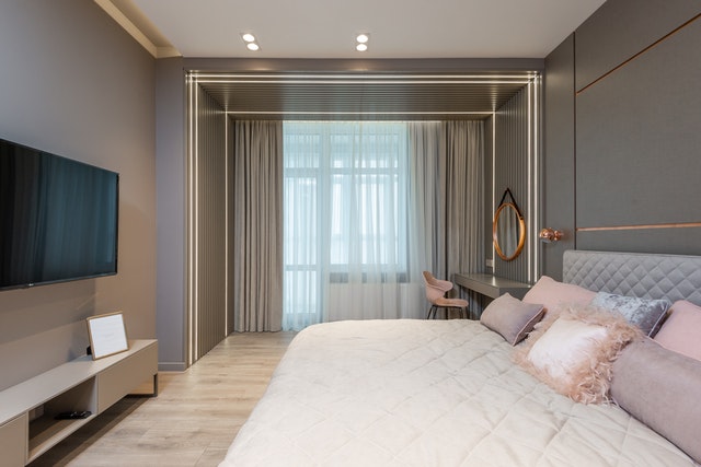 Contemporary bedroom interior with comfortable bed and TV set